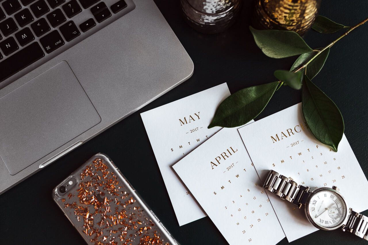 Home office desk with Macbook, iPhone, calendar, watch & organizer